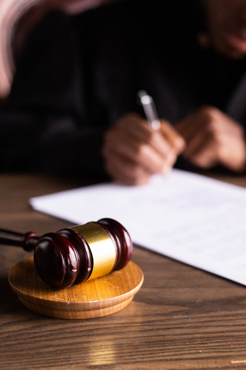 Judge signing documents at desk with focus on gavel, representing law and justice.